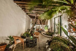 A cozy indoor garden with a wooden pergola, seating area, and various potted plants. - Los Lirios Hotel Rural (Tías)