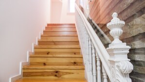 Un escalier en bois avec des balustrades blanches et un mur en pierre.