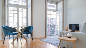 Un salon moderne avec un canapé, un téléviseur et une table à manger avec des chaises.