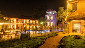 A nighttime view of a hotel with a swimming pool, a wooden deck, and a garden area. - Tam Coc Lavender Homestay (Nam Hoa Lu)