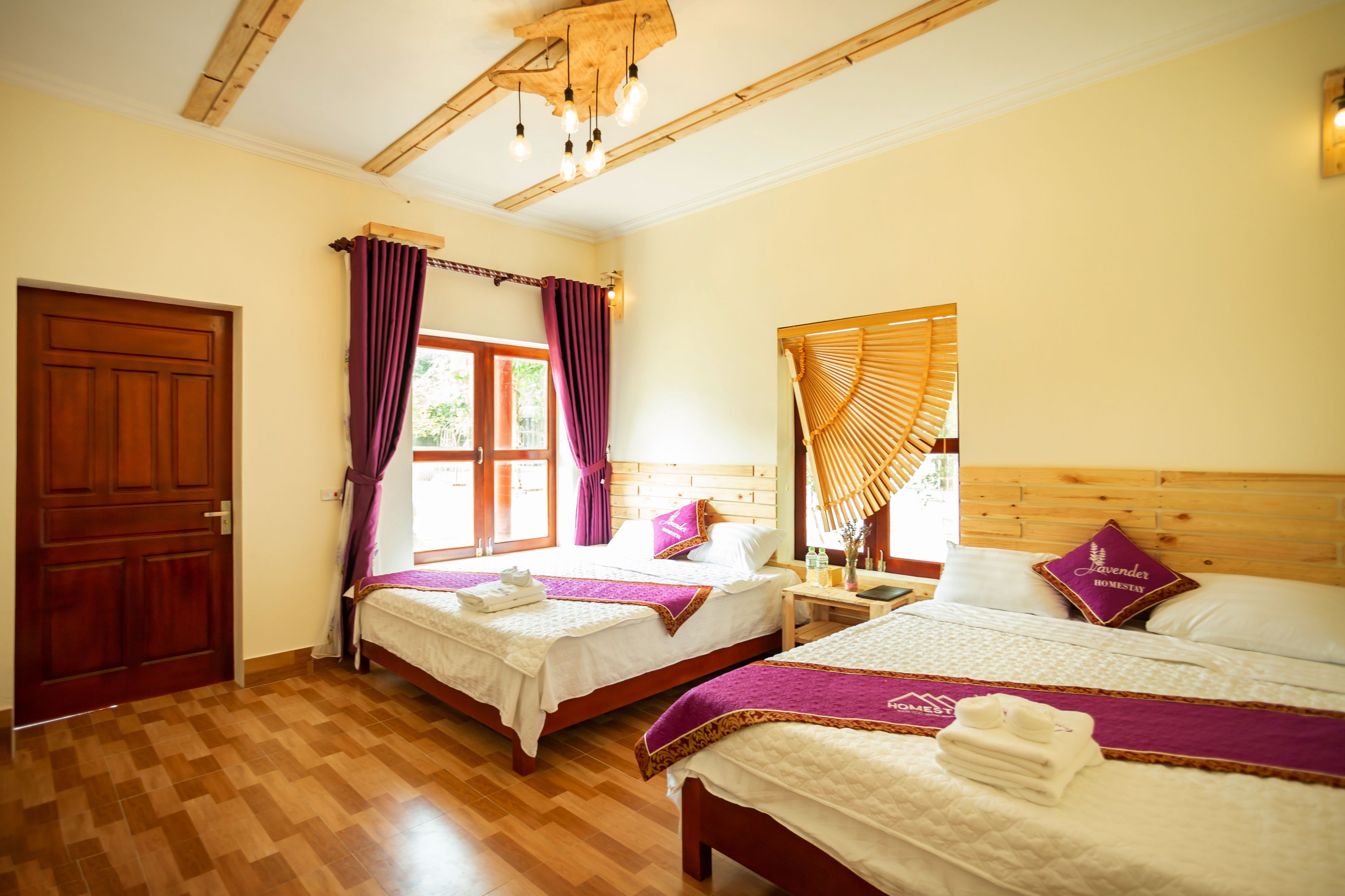 Una camera d'albergo con due letti, pavimento e soffitto in legno, e una finestra con tende.