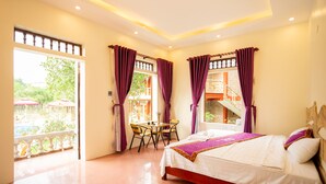 A hotel room with a bed, a table with chairs, and a balcony with umbrellas. - Tam Coc Lavender Homestay (Nam Hoa Lu)