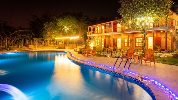 A nighttime swimming pool area with a well-lit building, lounge chairs, and a clear view of the pool. - Tam Coc Lavender Homestay (Nam Hoa Lu)