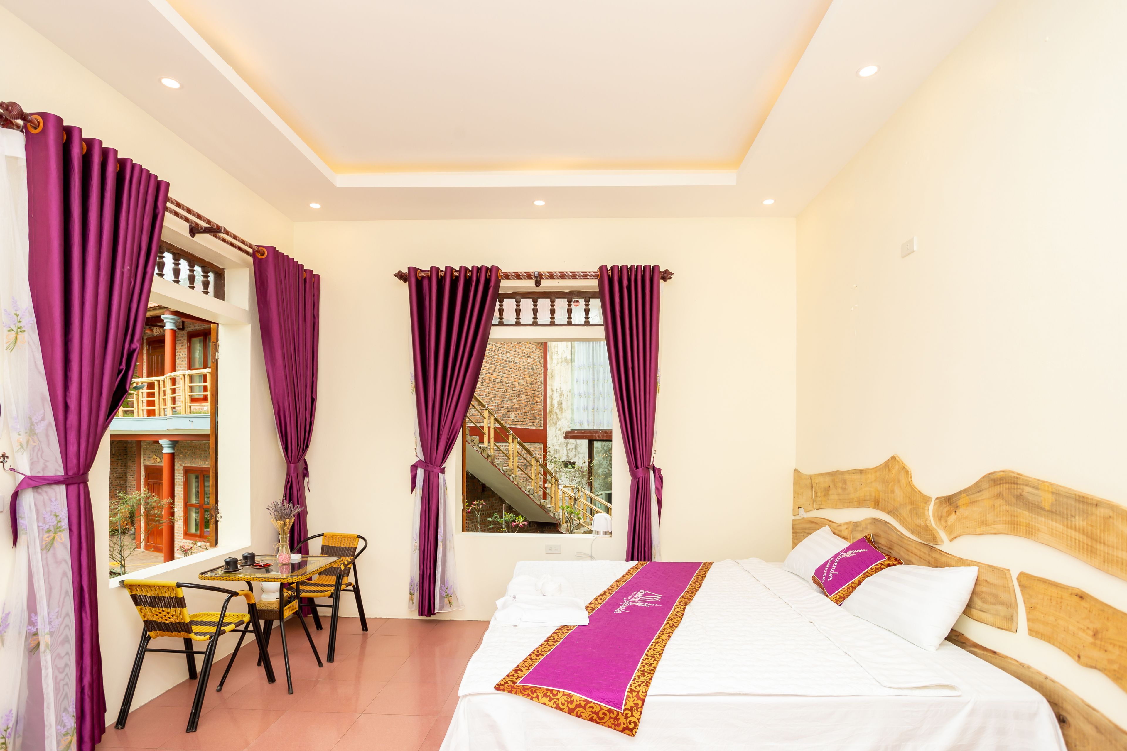 Ein Hotelzimmer mit Bett, Esstisch und Stühlen sowie violetten Vorhängen.