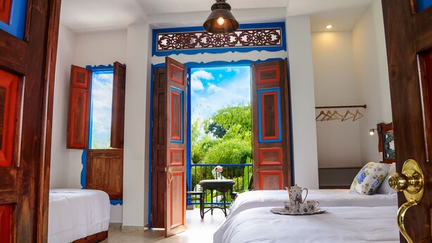 A hotel room with two beds, a balcony with a view, and a hanging light fixture. - Balsora Hotel Boutique (La Tebaida)