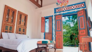 A bedroom with a bed, a wooden bench, and a view of the outdoors through a door. - Balsora Hotel Boutique (La Tebaida)