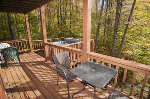 A wooden deck with a hot tub, two chairs, and a table. - Yukon Cornelius (Davis)