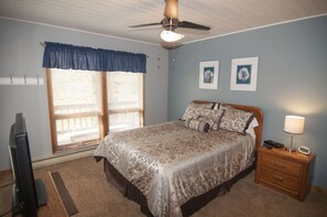 A bedroom with a bed, a nightstand, a lamp, a ceiling fan, and two framed pictures on the wall. - Yukon Cornelius (Davis)