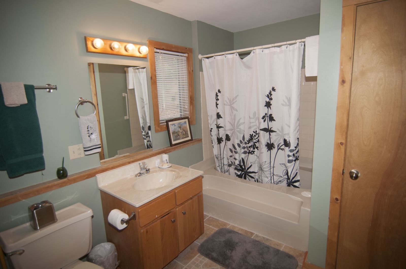 A bathroom with a sink, mirror, toilet, and shower curtain.