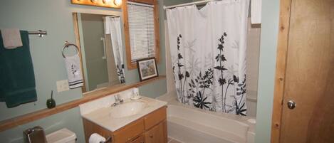 A bathroom with a sink, mirror, toilet, and shower curtain.