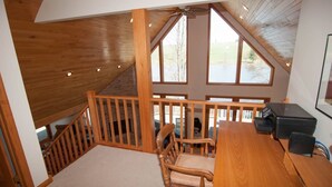A wooden interior with a desk, chairs, and a staircase leading to an upper level. - Woodland Pond (Davis)