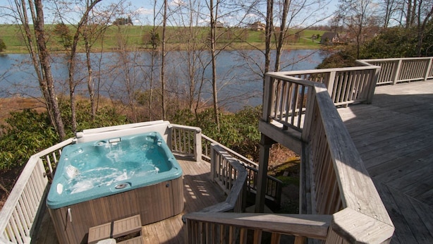 A hot tub on a wooden deck with a view of a lake and trees. - Woodland Pond (Davis)