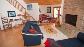 A spacious living room with a wooden staircase, a fireplace, and a cozy seating area. - Woodland Pond (Davis)