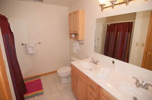 A bathroom with two sinks, a toilet, and a shower area.