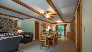 A cozy living room with a fireplace, a dining area, and a kitchen with wooden beams. - White Deer (Davis)