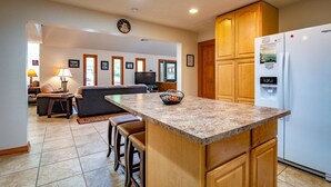 A kitchen with a granite countertop, wooden cabinets, and a built-in refrigerator. - White Diamond (Davis)