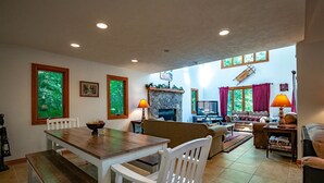 A spacious living room with a fireplace, a dining area with a wooden table and chairs, and a cozy seating area with sofas and a TV. - White Diamond (Davis)