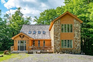 A lodge with a stone exterior, a wooden deck, and a covered porch.