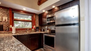 A modern kitchen with granite countertops, stainless steel appliances, and dark wooden cabinets. - Valley View Lodge (Davis)