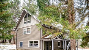 A two-story house with a gabled roof, large windows, and a stone foundation. - Valley View Lodge (Davis)