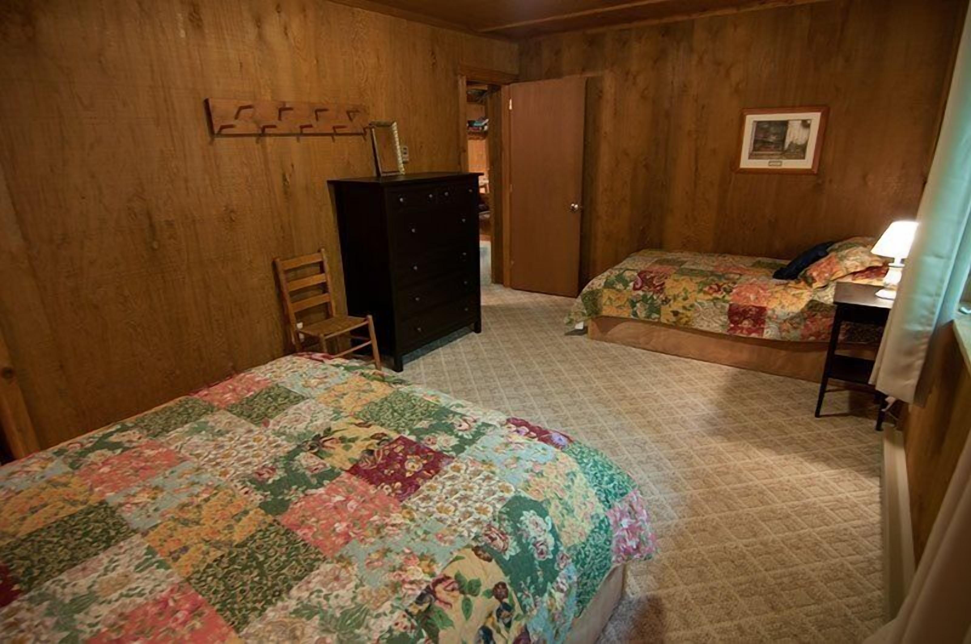 Una habitación con dos camas, un tocador y una silla.