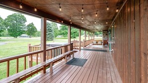 Une terrasse extérieure couverte, dotée de rampes en bois, de guirlandes lumineuses et d’un banc.