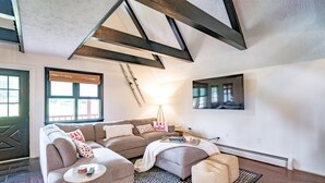 Un salon chaleureux avec un canapé d’angle, une petite table ronde et un tapis à motifs.