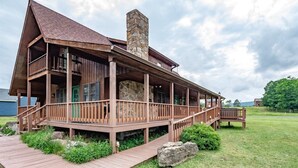 Une cabane en bois avec une cheminée en pierre, une véranda et une terrasse en bois.