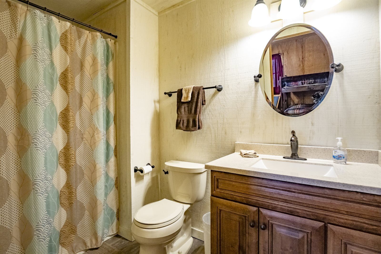 Une salle de bain comprenant des toilettes, un lavabo avec un miroir et un rideau de douche.