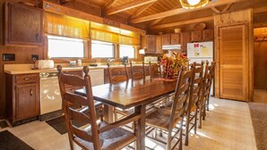 Un intérieur en bois comprenant une table à manger, des chaises, un coin cuisine et une pancarte indiquant « Bienvenue à la montagne ».