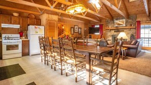 Une cuisine rustique avec des poutres en bois, une table à manger avec des chaises, un réfrigérateur et une cuisinière.