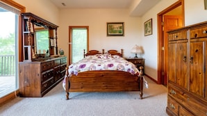 A bedroom with a wooden bed, a dresser, a nightstand, and a large wardrobe. - Sunset House (Davis)