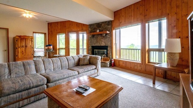 A cozy living room with a sectional sofa, a fireplace, a stone accent wall, and large windows offering a view. - Sunset House (Davis)