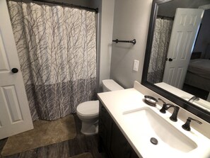 A bathroom with a toilet, sink, and shower curtain. - Talheim Village A9 (Davis)