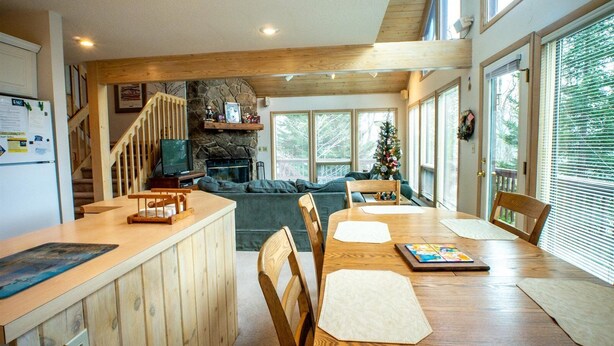 Un amplio salón con una mesa de comedor de madera, una chimenea y una pared decorativa de piedra.
