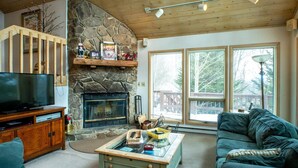 Una sala de estar acogedora con chimenea de piedra, televisor y un sofá cómodo.