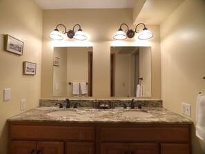 Un bagno con due lavandini, un grande specchio e illuminazione a parete.