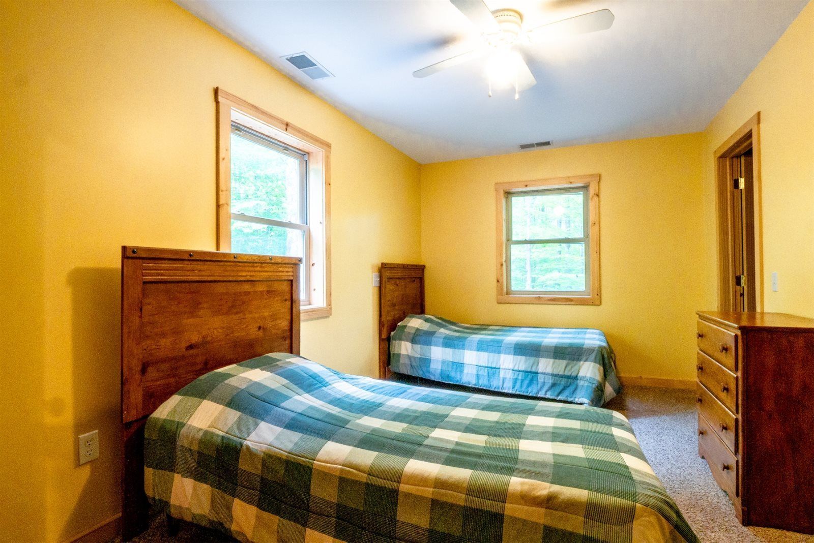 Une chambre avec deux lits, une commode et un ventilateur de plafond.