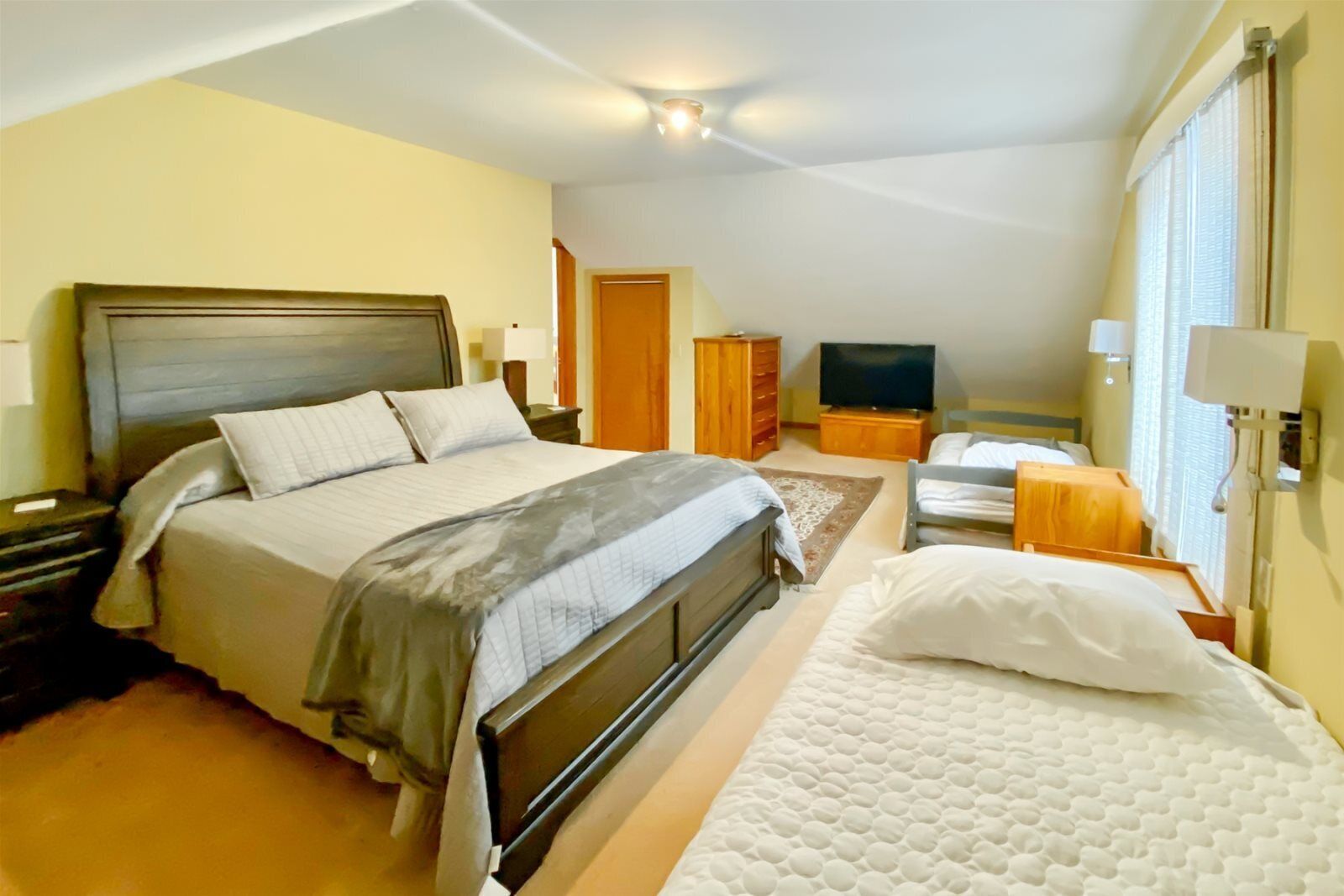 A bedroom with a large bed, a smaller bed, a TV, and a wardrobe.