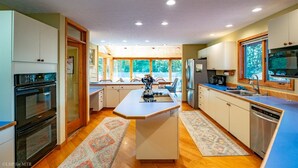 A modern kitchen with a central island, built-in appliances, and large windows offering views of the outdoors.