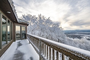 A snow-covered balcony with a view of a forest and distant landscape. - Spruce Lodge (Davis)