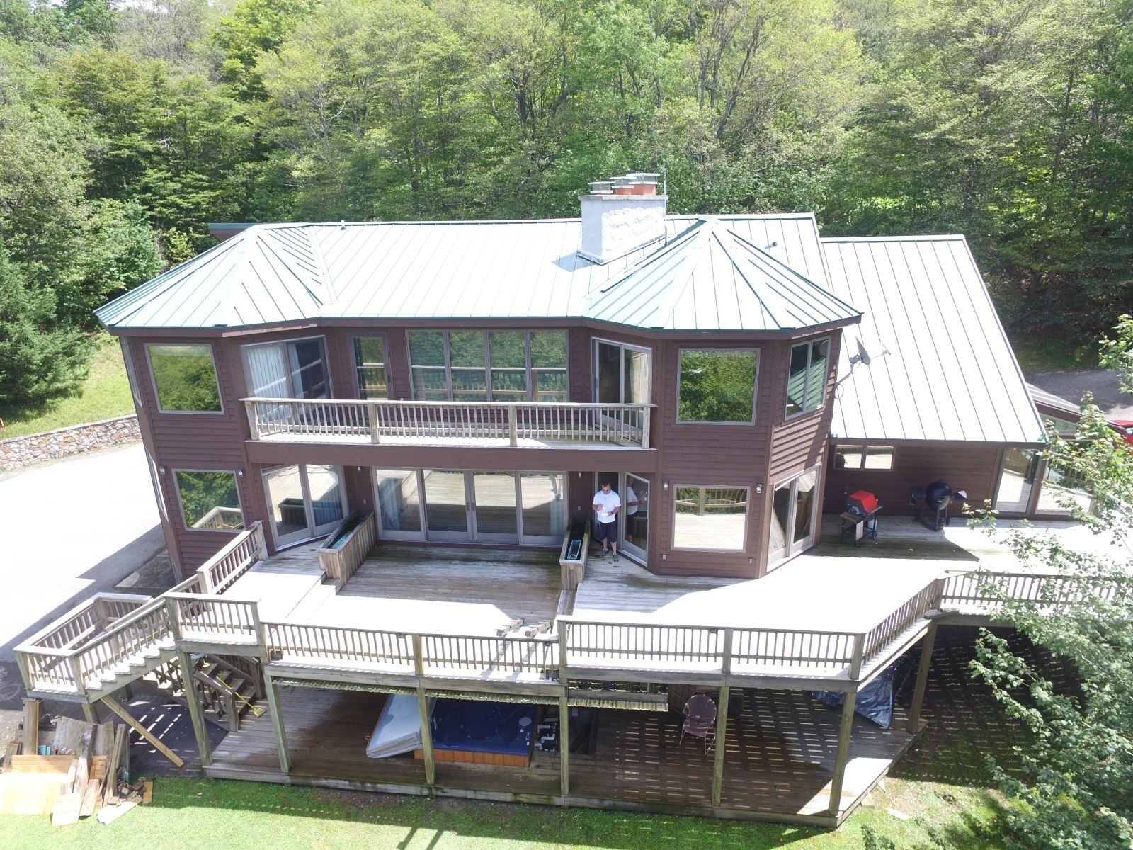 A two-story building with a balcony, a covered deck, and a hot tub.