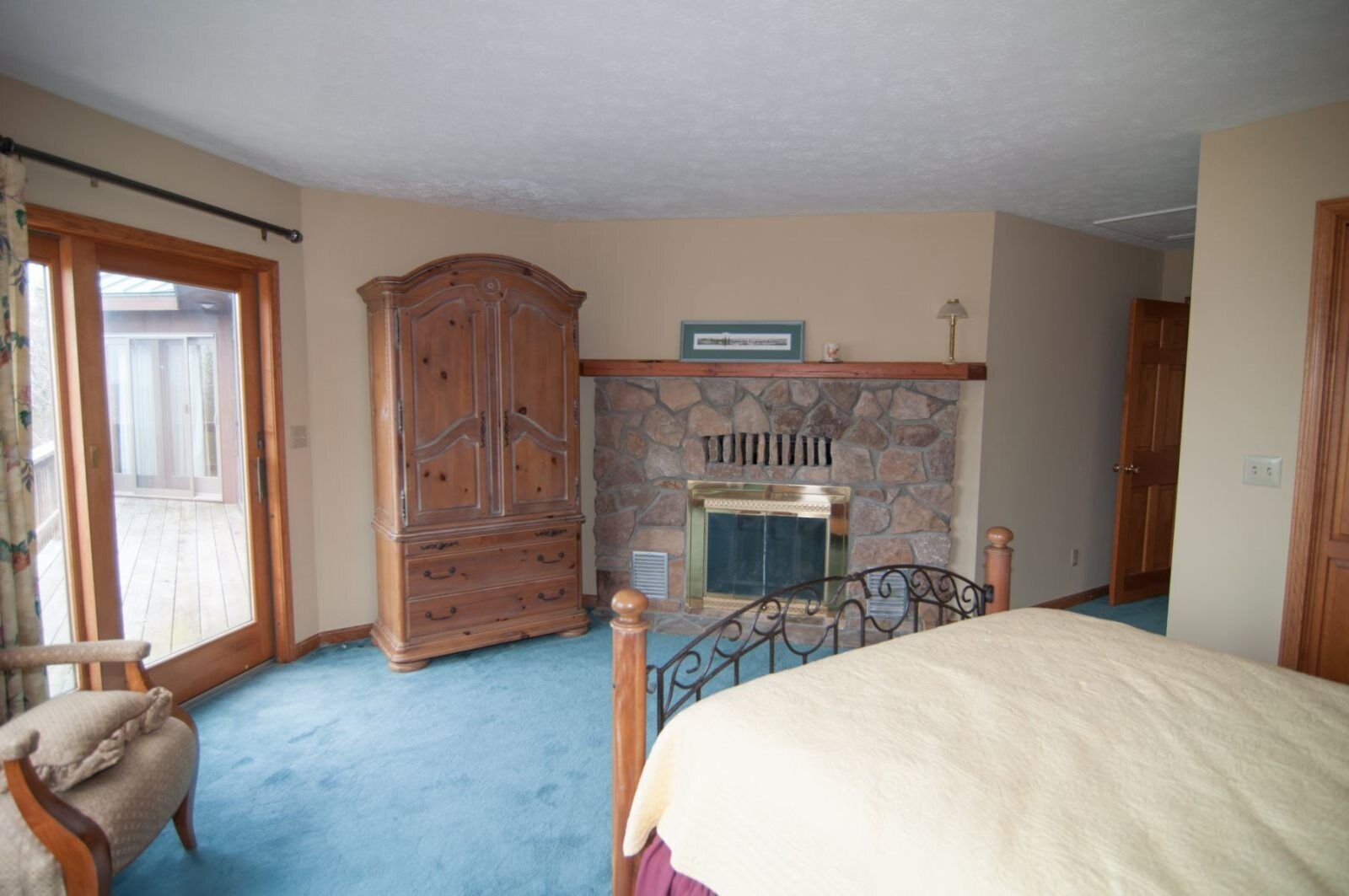 A bedroom with a large wardrobe, a stone fireplace, and a bed.