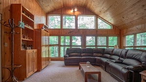 Ein gemütliches Wohnzimmer mit einer großen Eckcouch, Holzschränken und einem Glastisch.