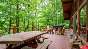 An outdoor deck with wooden furniture, including a table and chairs, surrounded by a wooden railing. - Our Greyt Escape (Davis)