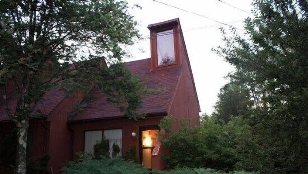 A red wooden house with a sloped roof and a visible chimney. - Pendletonheim 23 (Davis)