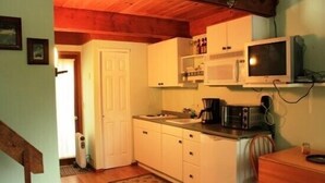 A compact kitchen with white cabinets, a microwave, a toaster, and a small dining table. - Pendletonheim 23 (Davis)