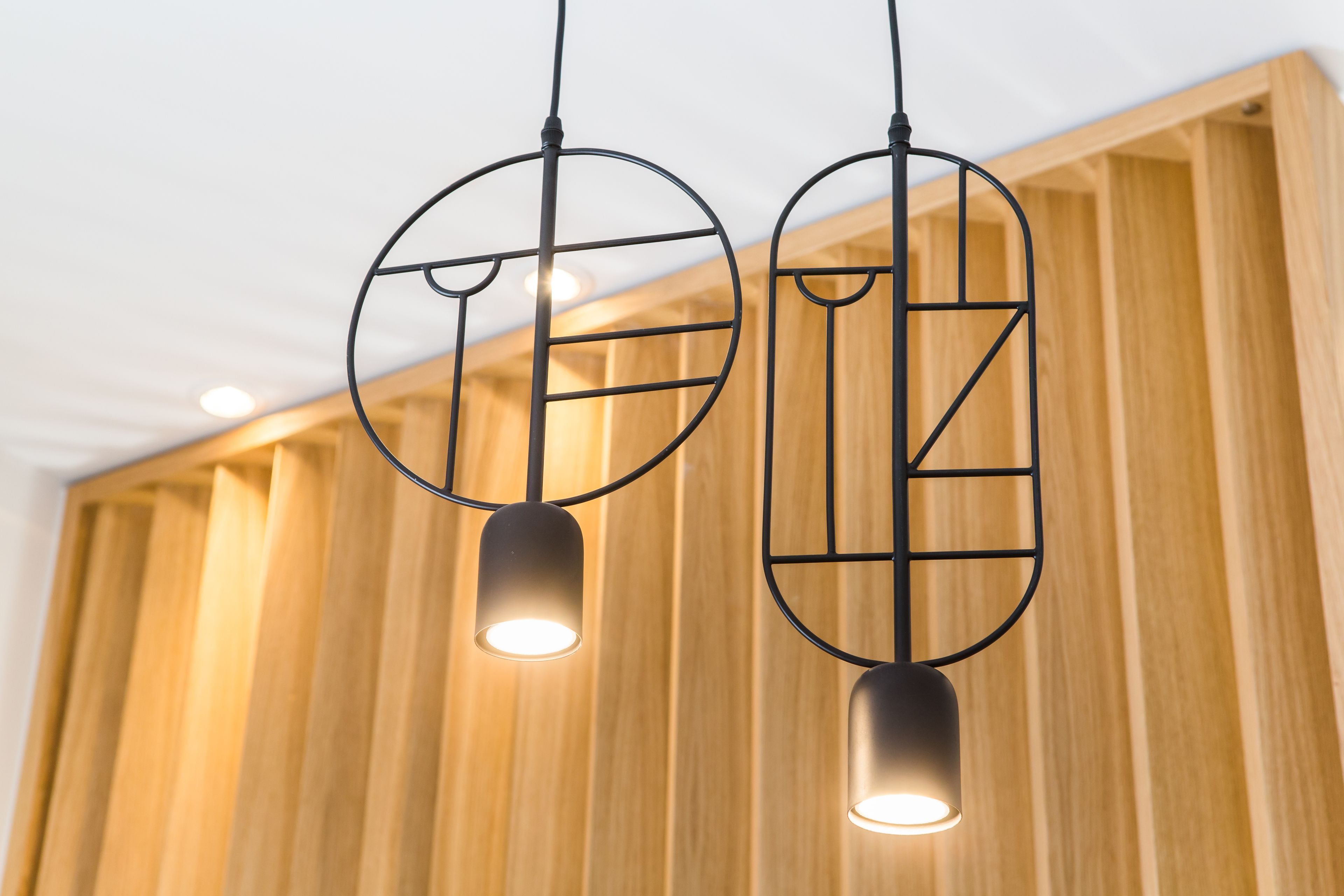 Zwei pendelnde Lampen mit geometrischen Mustern hängen von der Decke.