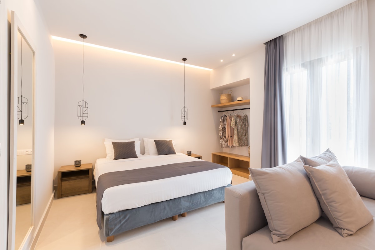 A modern bedroom with a large bed, bedside tables, a wardrobe, and a sofa.
