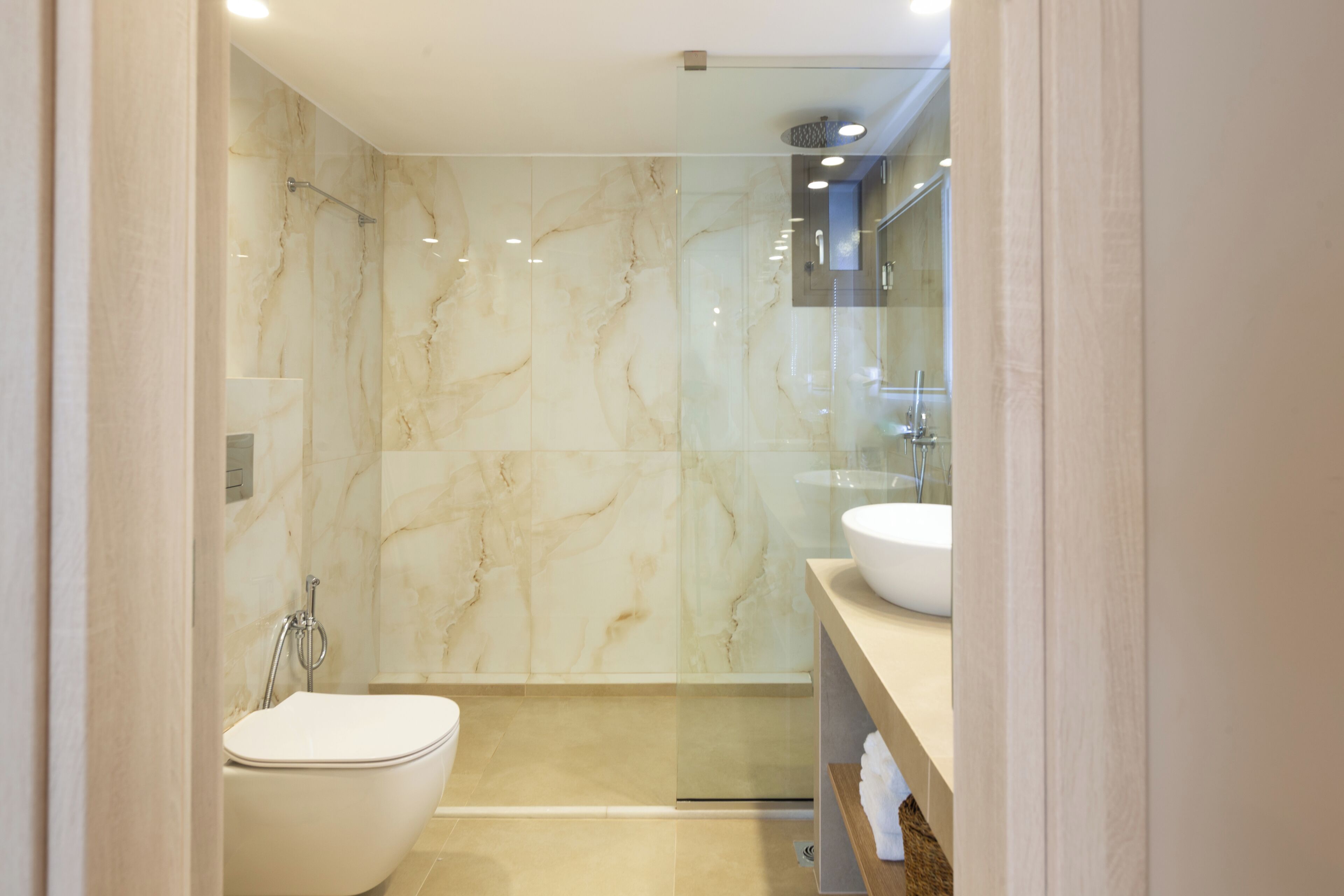 Un baño moderno con inodoro, cabina de ducha de vidrio y tocador con lavabo.